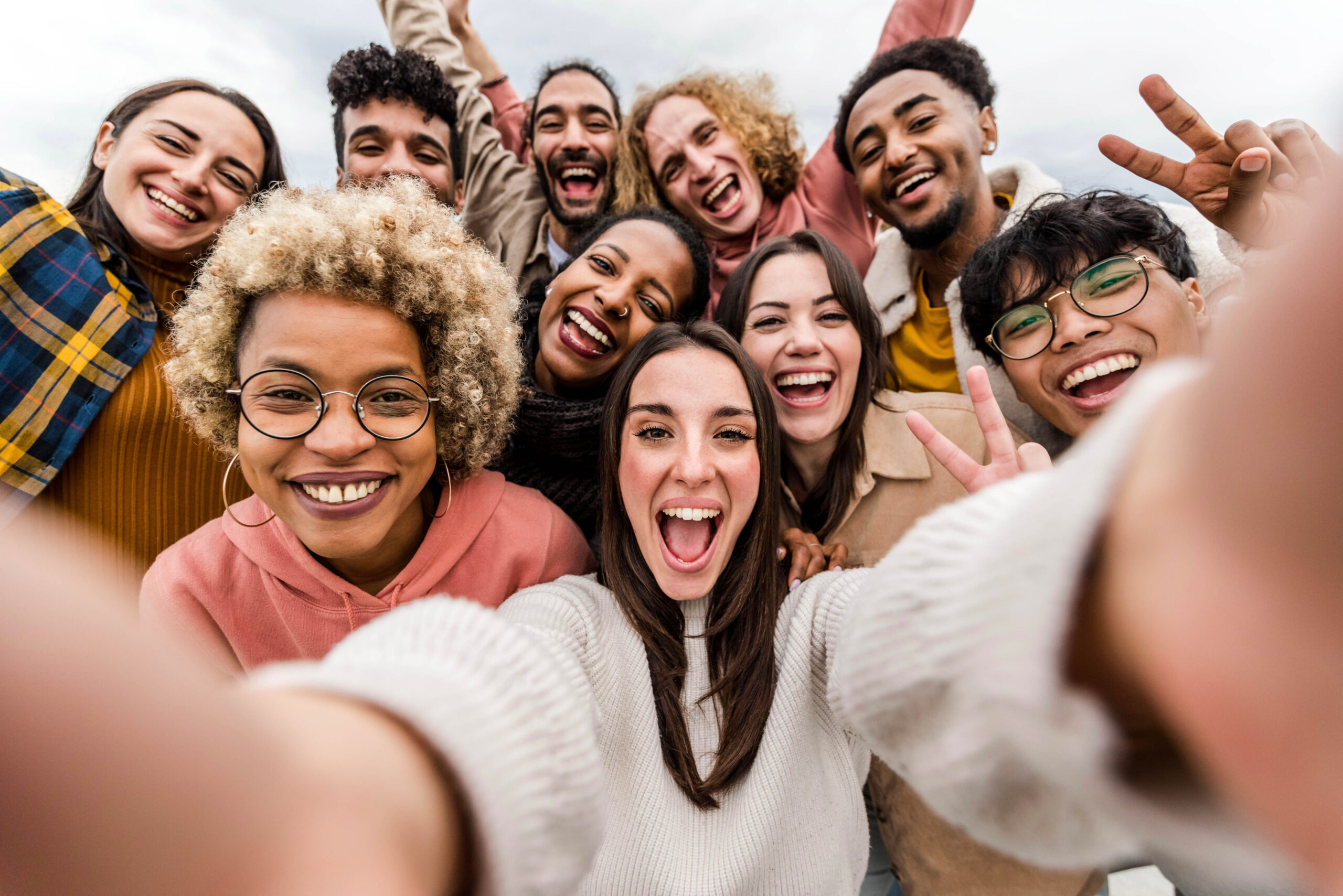 Groupe divers de jeunes souriants prenant un selfie, exprimant la joie et la convivialité.